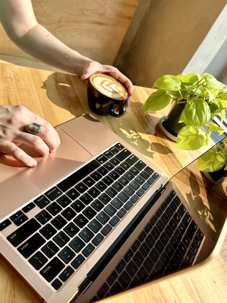 Organized and beautiful workspace with computer, plant, and coffee to help create a clear and focused mind.